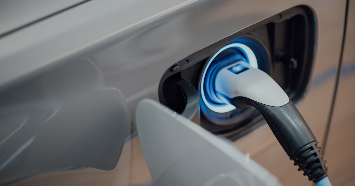 Electric car parked at a charging station beside a modern commercial building