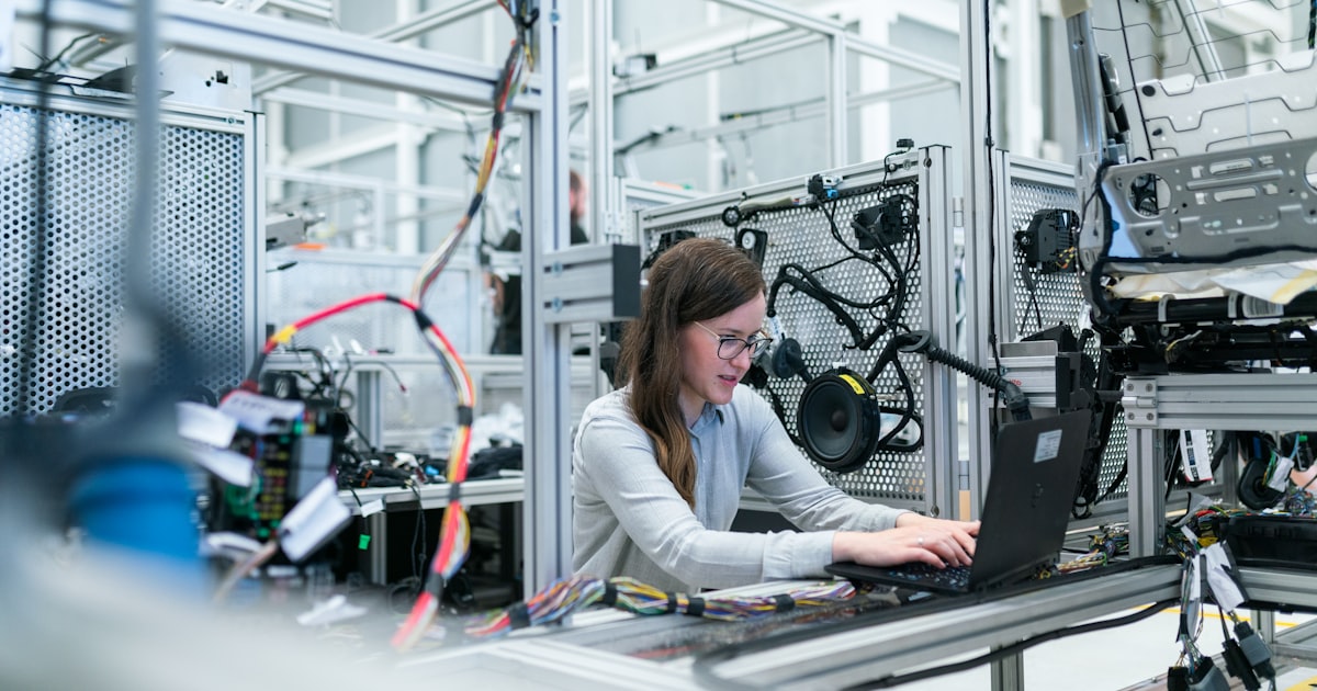Technician in safety glasses servicing industrial equipment controls