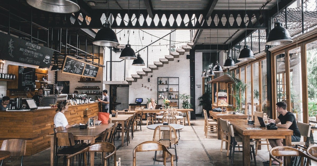 Interior of a large cafe or restaurant with long communal tables and seating