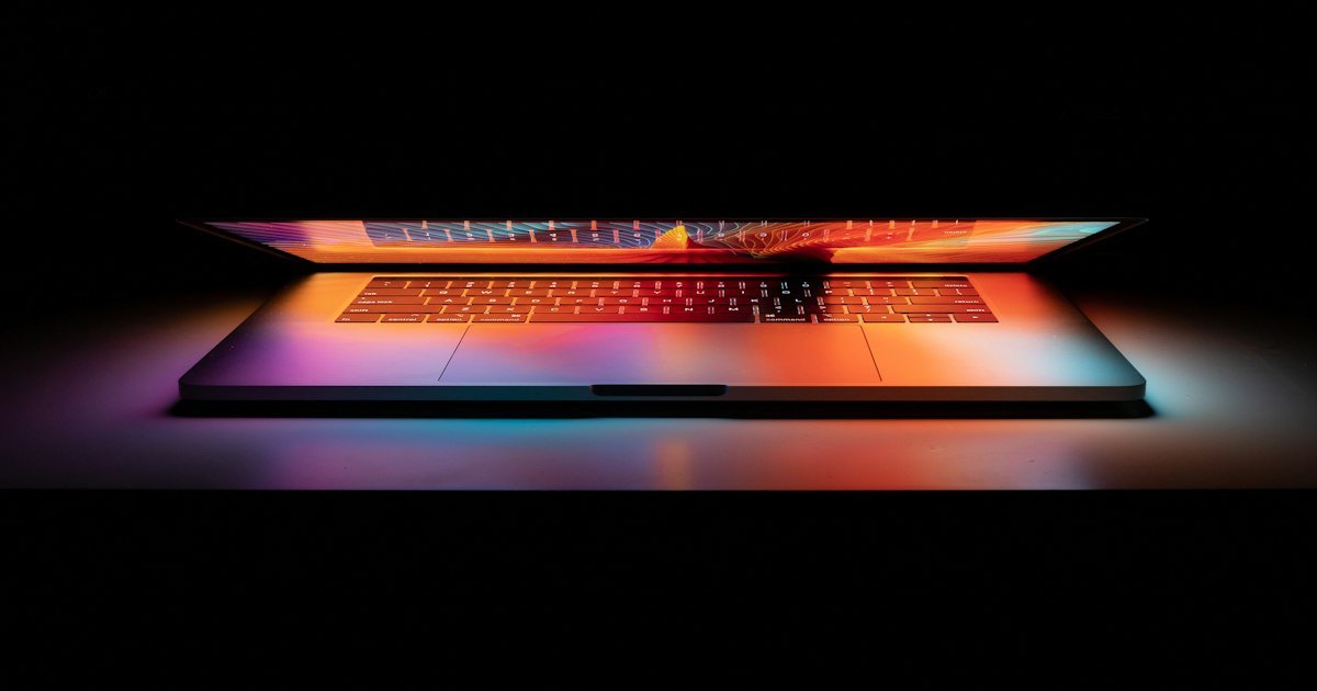 An open laptop on a desk showing a colourful abstract image on its screen