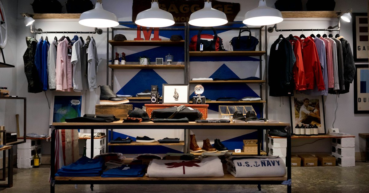 Interior of a clothing boutique with racks of shirts, shelving and display tables